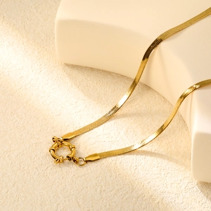 Macro view of golden flat snake chain with decorative round spring sailor clasp