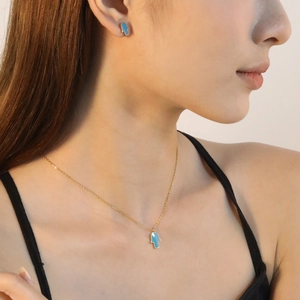 Parure collier et boucles d'oreilles dorés avec pendentif Main de Fatma bleue sur un mannequin