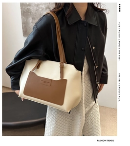 Detail view of contrast color tote bag with caramel leather pocket and embossed fashion text