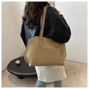 Detail of khaki leather tote bag showing a side view on model with adjustable strap