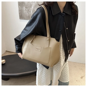 Détail du grand sac cabas en cuir kaki avec texte embossé porté par un mannequin
