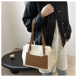 Detailed view of two-tone tote bag with brown leather pocket and refined stitching