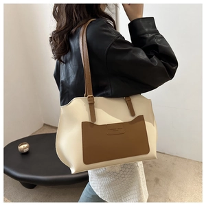 Détail d'un sac cabas bicolore avec logo embossé et texture de cuir de qualité