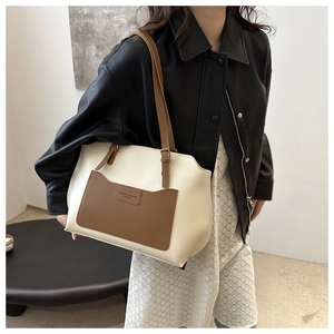 Détail du sac cabas bicolore crème et marron porté par un mannequin en mode urbain