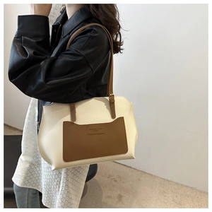 Detail view of contrast color tote bag showing brown leather pocket and white leather texture