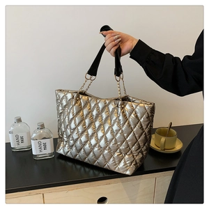 Detail of champagne gold quilted tote with metallic texture and gold chain strap link