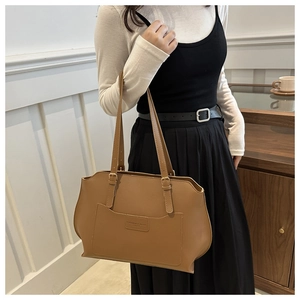 Détail du cabas en cuir caramel montrant la poche décorative et le logo embossé