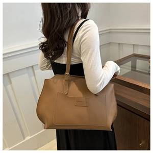 Détail de la bandoulière réglable et du logo embossé sur le sac cabas marron