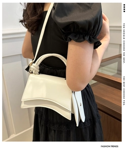 Détail d'un sac à main en cuir blanc avec base incurvée et poignée nouée sur modèle