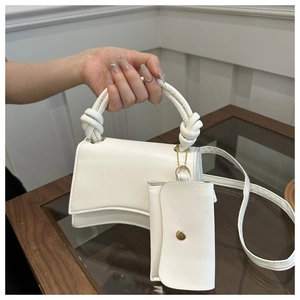 Détail d'un sac à main en cuir blanc avec poignée nouée et petite pochette assortie