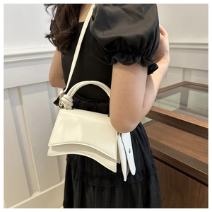 Détail du sac à main sablier blanc avec poignée nouée sur une robe noire en studio photo