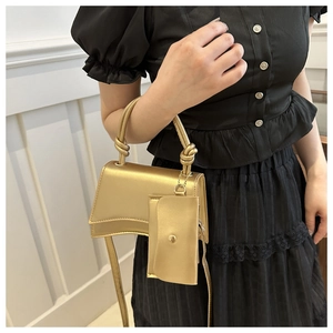 Détail du sac à main doré en croissant avec poignée nouée et breloque porte-monnaie