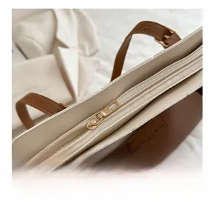Détail de la fermeture éclair dorée lisse sur un sac cabas bicolore élégant
