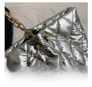 Macro detail of silver quilted tote bag showing fine stitching and gold chain strap