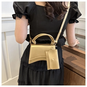 Détail du sac sablier champagne doré avec poignée nouée et mini breloque amovible