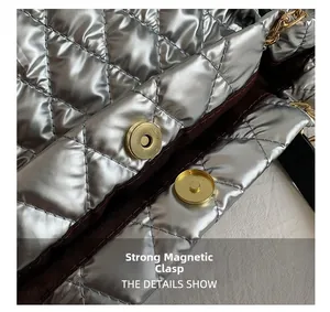 Detail of strong magnetic buckle on a metallic silver quilted tote bag with brown lining