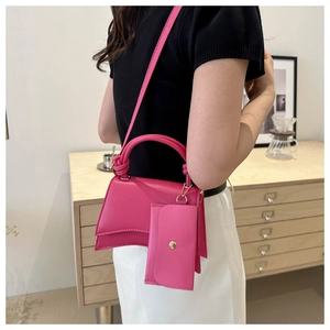 Détail d'un sac à main rose avec base incurvée et pochette de rangement amovible