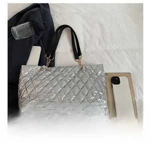 Detail view of silver quilted tote bag with black faux leather handles and metal chains