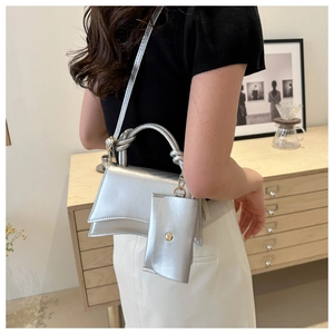 Détail du sac à main argenté métallisé avec poignée nouée et design incurvé en sablier