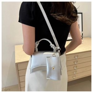 Sac à bandoulière argenté avec poignée nouée et porte-monnaie porté par un mannequin