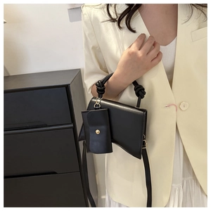 Détail du sac à main noir incurvé avec poignée nouée et petit porte-monnaie amovible
