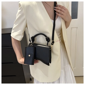 Détail du sac à main noir élégant avec base incurvée, poignée nouée et finitions dorées