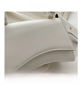Détail de la base incurvée en sablier et des surpiqûres sur un sac à main blanc chic