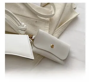 Détail d'un mini charm en similicuir blanc avec bouton pression doré et chaîne en métal