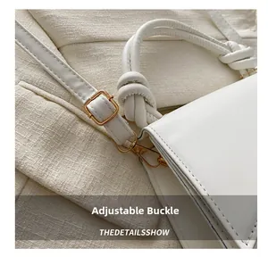 Détail du sac bandoulière en cuir blanc avec boucle dorée et coutures de précision