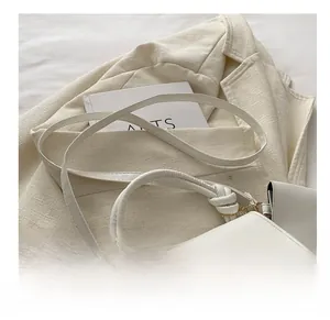 Gros plan d'un sac bandoulière en cuir blanc avec poignée nouée et sangle réglable