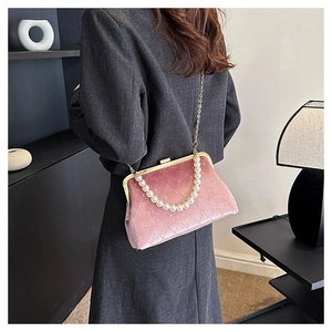 Detail of pink velvet crossbody bag with quilted pattern and pearl handle on a model