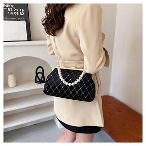 Detail of vintage quilted velvet bag featuring pearl handle and gold chain strap
