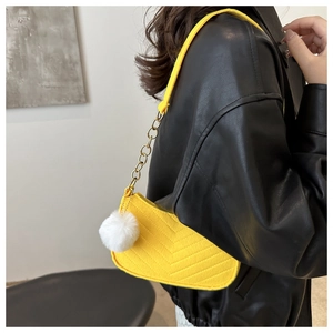 Primo piano della borsa in feltro giallo con cuciture a V e catenina in metallo dorato.
