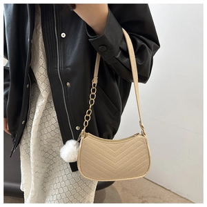 Dettaglio della borsa hobo trapuntata beige con cuciture a V e ciondolo a forma di palla