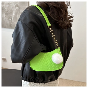 Close-up of neon green quilted shoulder bag with white faux fur pompom and gold chain strap