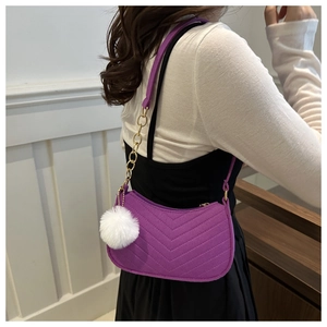 Detail view of purple crescent felt shoulder bag with V-shaped quilting and plush pom-pom charm