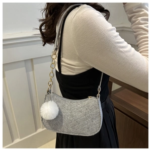 Detail of grey felt shoulder bag with quilted diamond pattern and white faux fur pompom