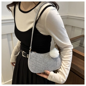 Dettaglio della borsa a spalla in feltro grigio chiaro con cuciture a V e pompon bianco