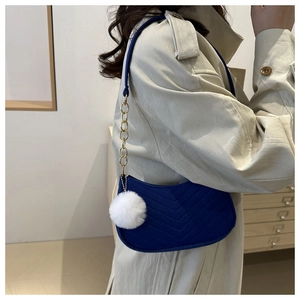 Dettaglio della borsa sottobraccio in feltro blu navy con trapuntatura a onde e pompon