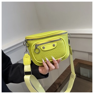 Macro detail of neon green crocodile texture leather bag with silver rivets and zippers