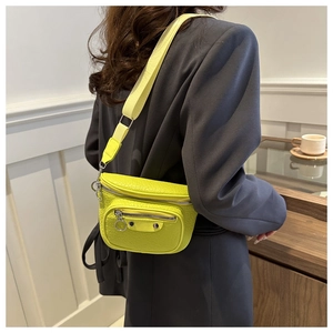 Close-up of vibrant lime green pleated crossbody bag featuring metal rivets and wide strap