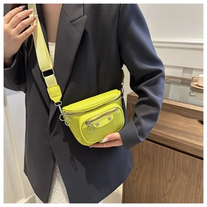 Detail of neon green crocodile pattern belt bag with silver studs and wide strap