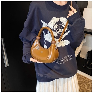 Braune Hobo-Tasche mit G-Anhänger und verstellbarem Riemen auf blauem Sweatshirt