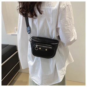 Detail of black pebbled leather crossbody bag with silver studs on white shirt