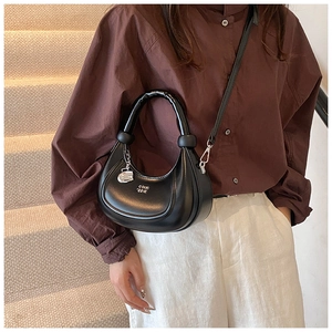 Modische schwarze Halbmond-Tasche kombiniert mit braunem Hemd und weißer Hose