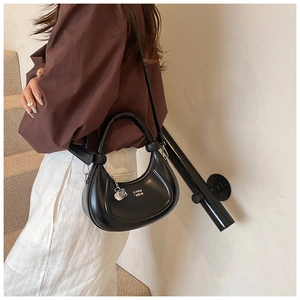 Detail der schwarzen Halbmond-Tasche mit silbernem G-Anhänger an einem Model