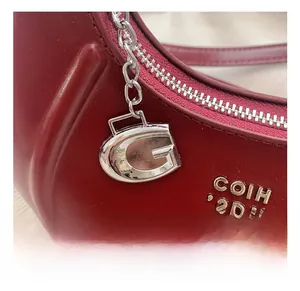 Detail der roten matten Ledertasche mit silbernen Beschlägen und G-förmigem Anhänger