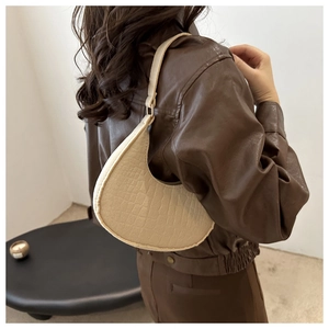Detail of beige faux leather hobo bag with crocodile pattern and matte texture
