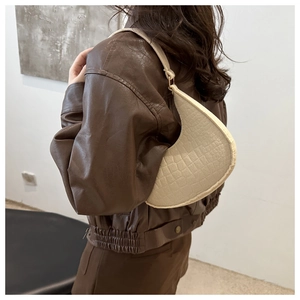 Vue détaillée du sac croissant crème avec texture croco sur une veste en cuir