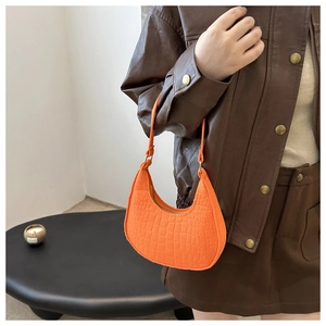 Close-up of bright orange faux leather shoulder bag with crocodile pattern texture
